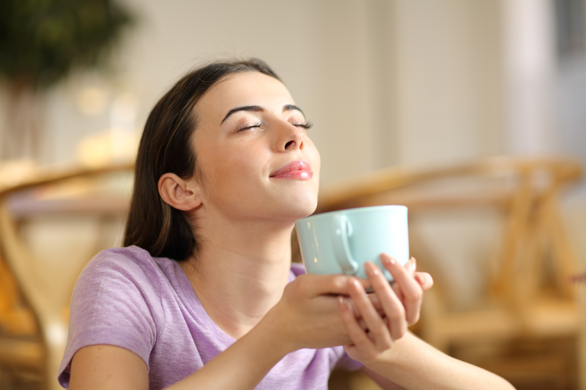Woman smelling coffee breathing at home
