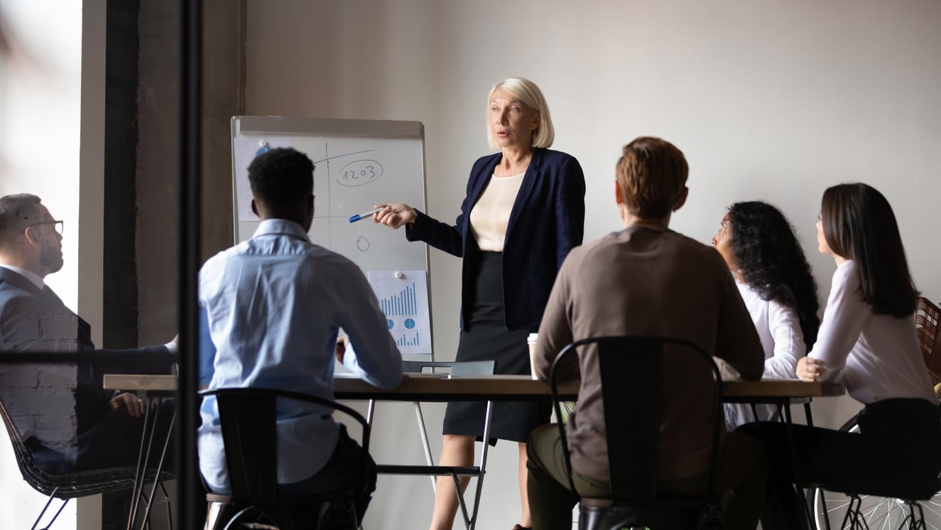 Aged trainer teaches diverse staff during corporate training at boardroom